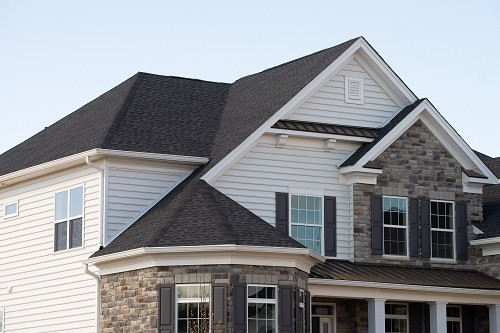 Large house with a conical roof, vinyl siding, and stone veneer. 