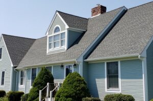 A Cape Cod style house with a gray shingle roof. 