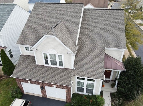 A yellow house with a brown shingle roof. 