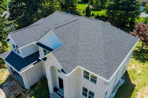Aerial view of asphalt shingles construction site roofing the house with new windows.