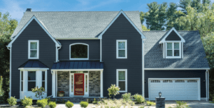 Beautiful two-story home with dark blue siding and stone surrounding the front door