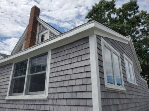 Corner of home with grey cedar shake siding and white trim